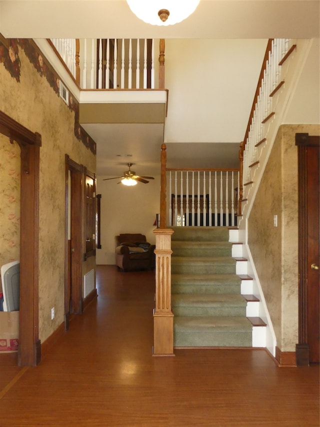 staircase featuring hardwood / wood-style floors, a towering ceiling, and ceiling fan