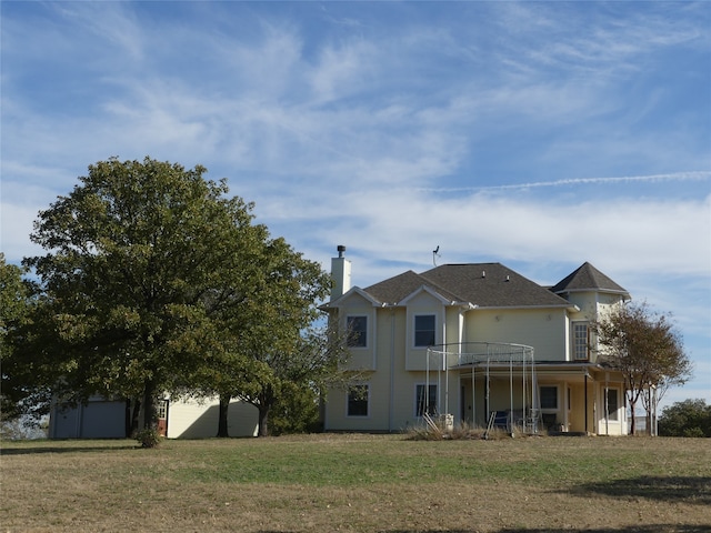 rear view of property featuring a balcony and a lawn