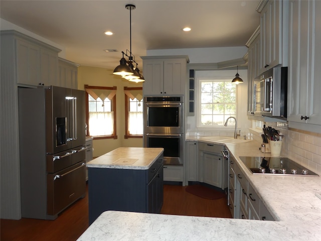 kitchen with pendant lighting, gray cabinetry, sink, a kitchen island, and stainless steel appliances