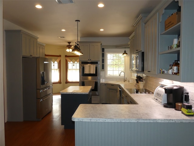 kitchen with stainless steel appliances, kitchen peninsula, sink, and hanging light fixtures