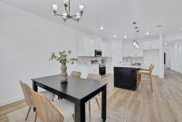 dining room with light hardwood / wood-style flooring, a notable chandelier, and sink