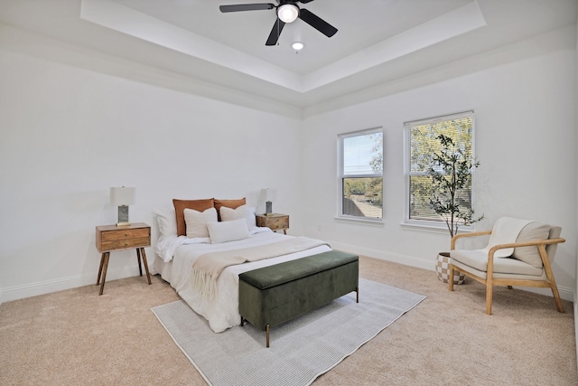 bedroom with light carpet, a raised ceiling, and ceiling fan