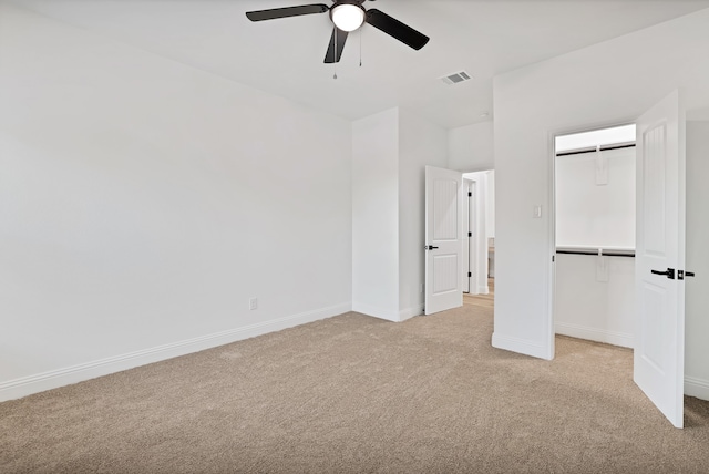 unfurnished bedroom with a closet, light colored carpet, and ceiling fan