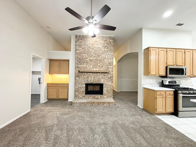 kitchen with light carpet, appliances with stainless steel finishes, ceiling fan, and a fireplace