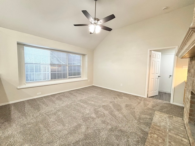 spare room with a fireplace, dark carpet, ceiling fan, and lofted ceiling