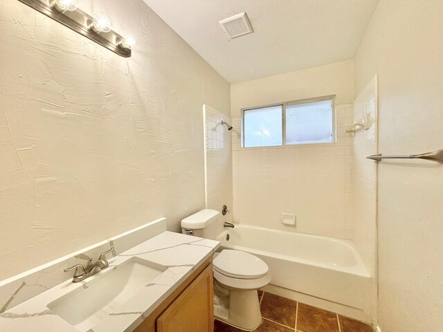 full bathroom featuring vanity, tile patterned flooring, tiled shower / bath combo, toilet, and a textured ceiling