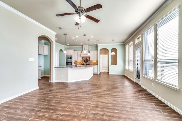 unfurnished living room featuring hardwood / wood-style flooring, crown molding, and ceiling fan