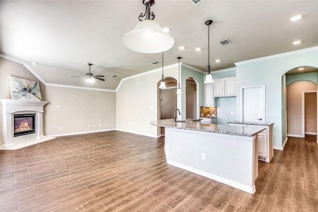 kitchen with white cabinetry, sink, a center island with sink, and decorative light fixtures