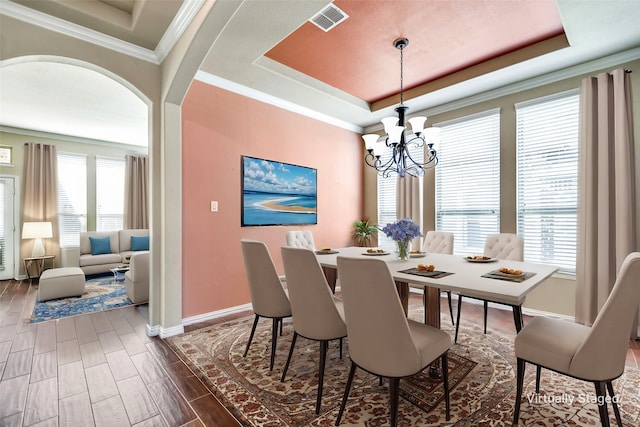 dining room featuring ornamental molding, plenty of natural light, a chandelier, and a tray ceiling