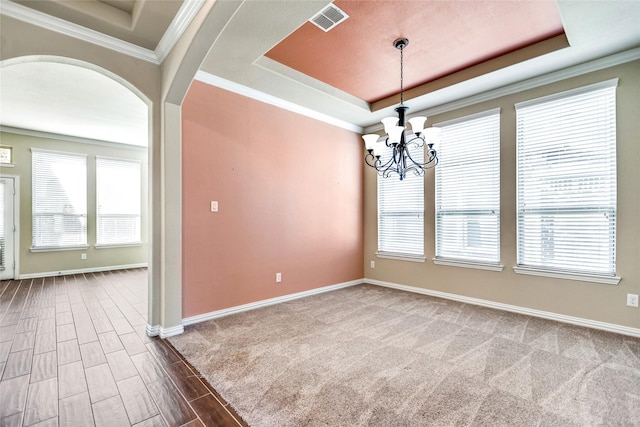 empty room with crown molding, a chandelier, and a tray ceiling