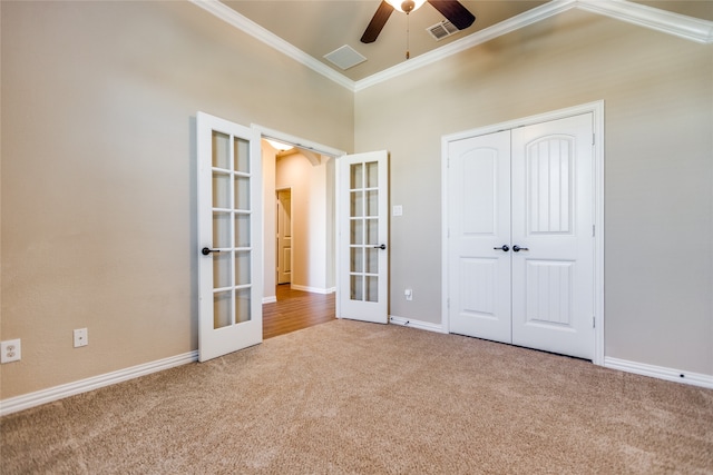 unfurnished bedroom with french doors, carpet flooring, ceiling fan, crown molding, and a closet