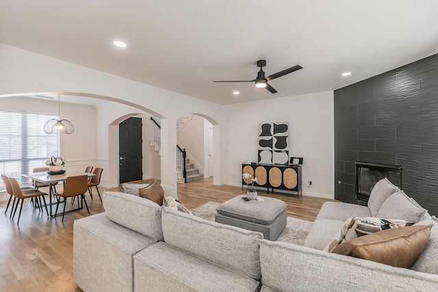 living room featuring ceiling fan, a fireplace, and light wood-type flooring