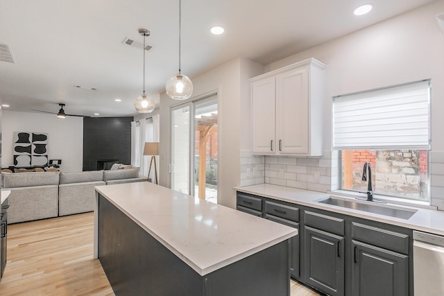 kitchen with sink, a center island, stainless steel dishwasher, white cabinets, and backsplash