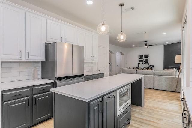 kitchen with white cabinetry, decorative backsplash, a center island, light hardwood / wood-style floors, and stainless steel appliances