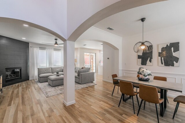 living room featuring light hardwood / wood-style flooring, ceiling fan, and a tiled fireplace