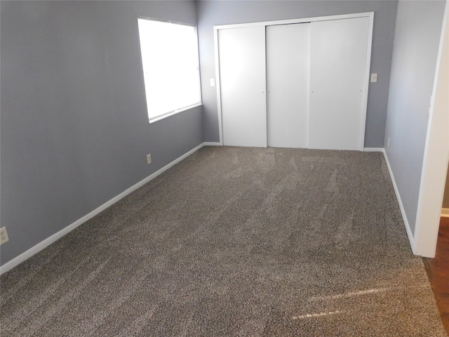 unfurnished bedroom featuring dark carpet and a closet