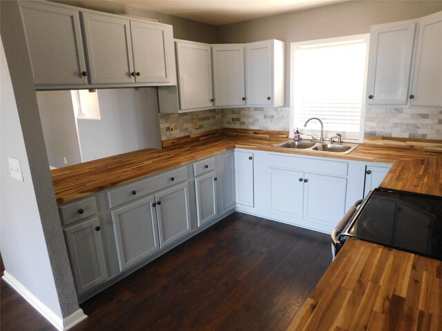 kitchen featuring dark wood-type flooring, white cabinetry, sink, and wooden counters