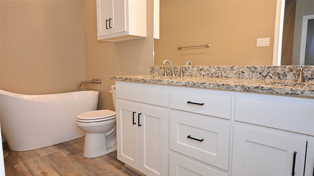 bathroom with a bathtub, vanity, wood-type flooring, and toilet