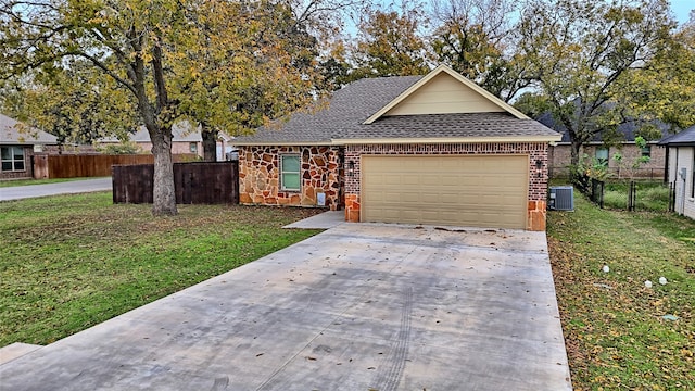 view of front of house featuring a garage, a front yard, and central AC