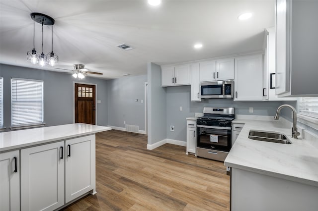 kitchen with white cabinetry, appliances with stainless steel finishes, sink, and light stone counters