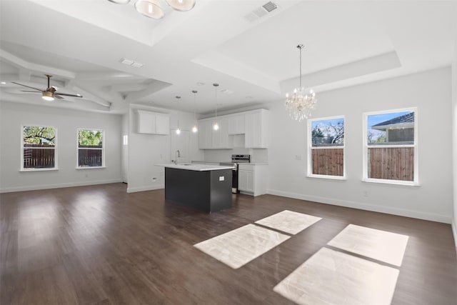 kitchen with dark wood-type flooring, white cabinets, hanging light fixtures, stainless steel range with electric cooktop, and an island with sink