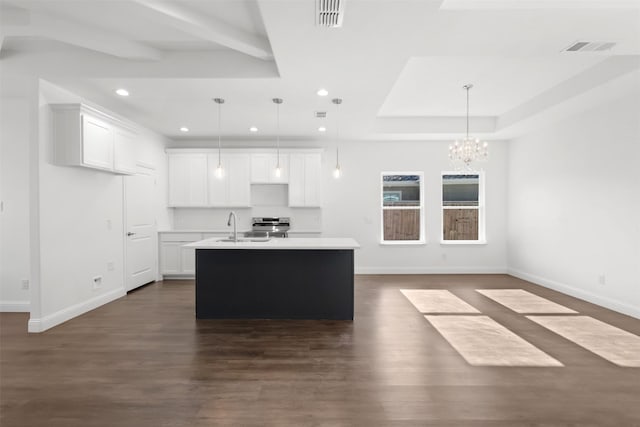 kitchen featuring white cabinets, pendant lighting, and a center island with sink