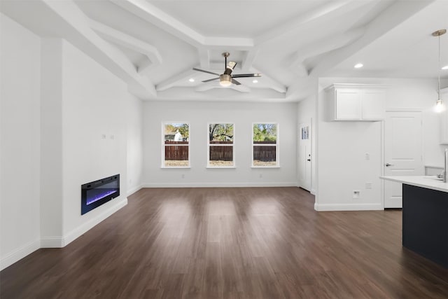 unfurnished living room with ceiling fan, beamed ceiling, and dark wood-type flooring