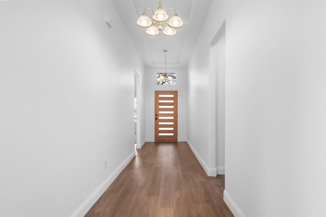 hallway with dark wood-type flooring and a chandelier