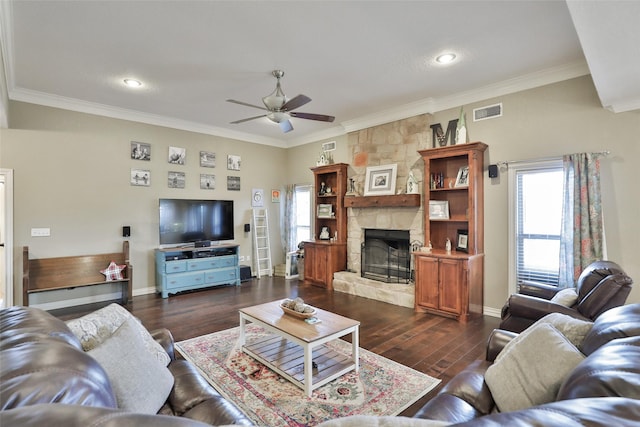 living room featuring ceiling fan, a stone fireplace, dark hardwood / wood-style flooring, and ornamental molding