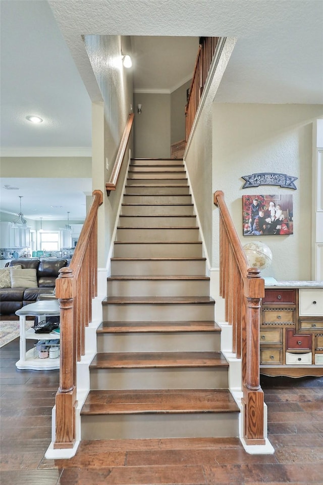 staircase featuring hardwood / wood-style floors, crown molding, and a textured ceiling