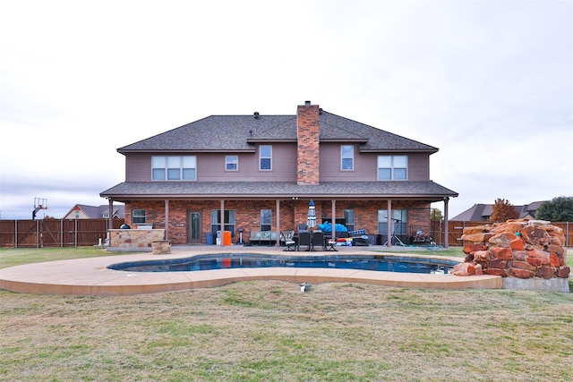 rear view of house with an outdoor living space with a fireplace, a patio area, and a yard