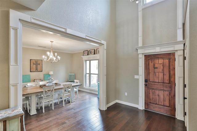 foyer entrance featuring ornamental molding, dark wood-type flooring, and a chandelier