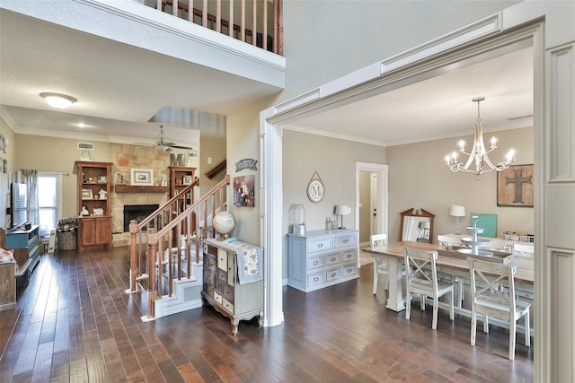 interior space featuring a stone fireplace, crown molding, a notable chandelier, and hardwood / wood-style flooring