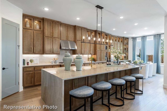 kitchen featuring a kitchen bar, light hardwood / wood-style floors, hanging light fixtures, and a spacious island