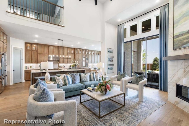 living room with ceiling fan, light hardwood / wood-style floors, and a high ceiling