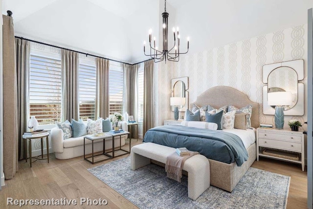 bedroom with hardwood / wood-style flooring, lofted ceiling, and an inviting chandelier