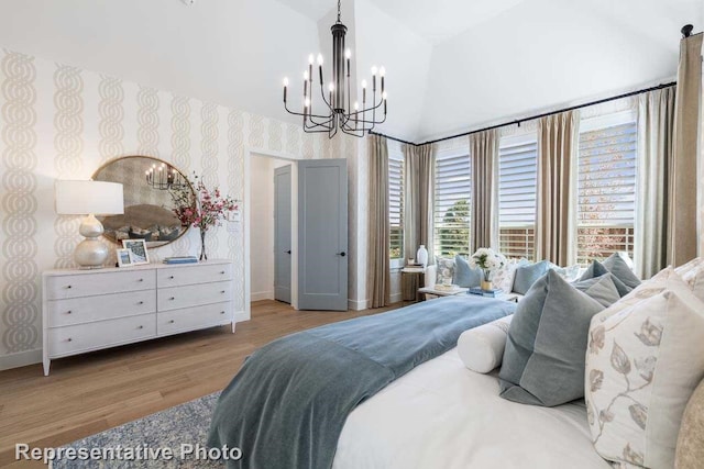 bedroom with light hardwood / wood-style floors, lofted ceiling, and an inviting chandelier