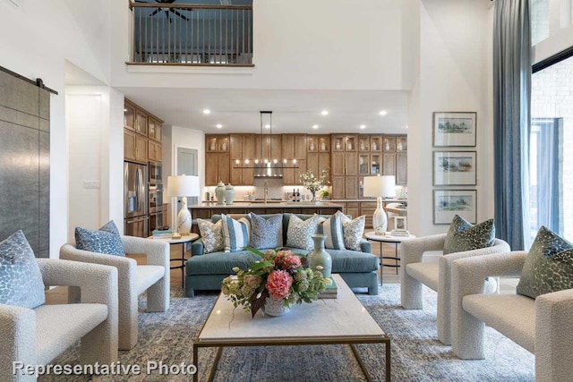 living room with a barn door, sink, and a high ceiling