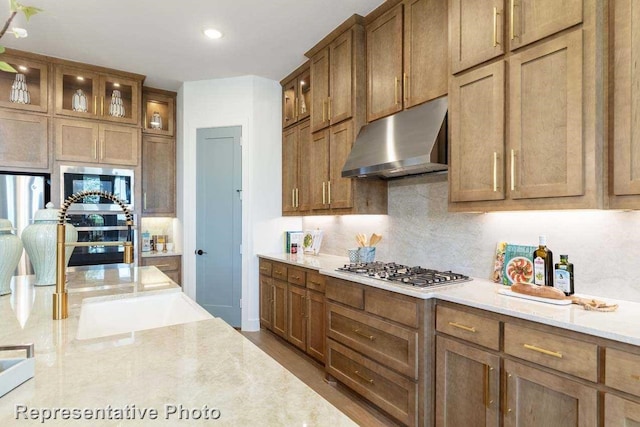 kitchen featuring decorative backsplash, light stone countertops, sink, and stainless steel gas cooktop