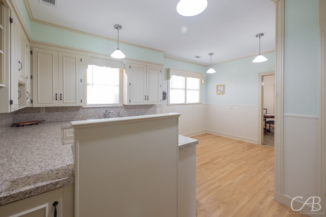 kitchen with decorative backsplash, crown molding, light hardwood / wood-style floors, and decorative light fixtures