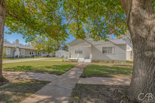 view of front of house with a garage, an outdoor structure, and a front yard