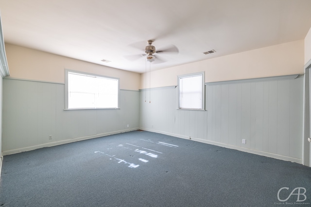 unfurnished room with dark carpet and ceiling fan