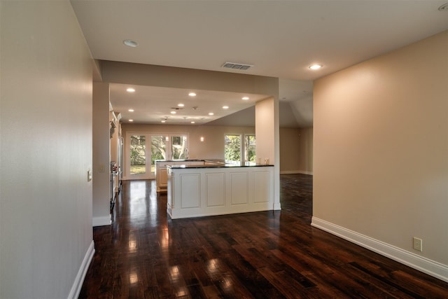 2516 Beefeater Dr, Wichita Falls, TX 76308 - kitchen with dark wood-style flooring, recessed lighting, dark countertops, white cabinets, and a peninsula