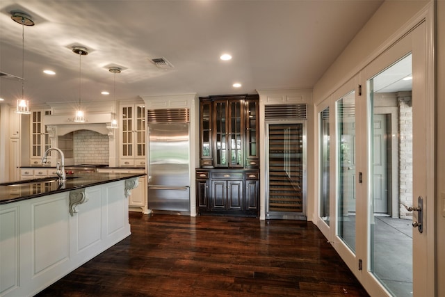 2516 Beefeater Dr, Wichita Falls, TX 76308 - kitchen featuring stainless steel built in refrigerator, beverage cooler, dark countertops, dark wood-type flooring, and decorative backsplash
