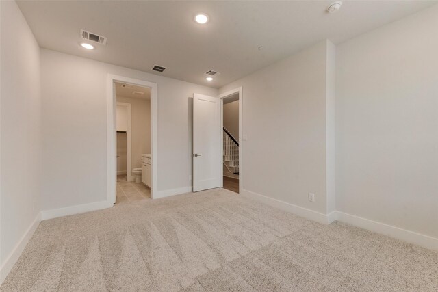 unfurnished bedroom with light carpet and ensuite bath