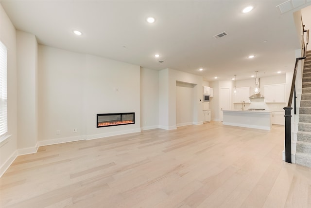 unfurnished living room featuring light hardwood / wood-style floors and sink