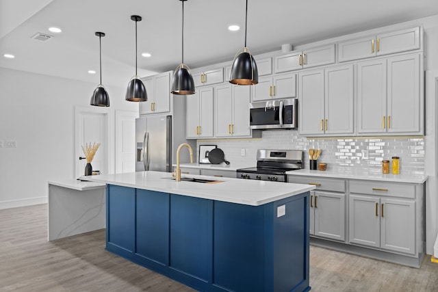 kitchen with sink, stainless steel appliances, an island with sink, light hardwood / wood-style floors, and decorative light fixtures