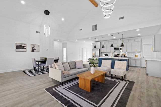 living room with an inviting chandelier, high vaulted ceiling, and light hardwood / wood-style flooring