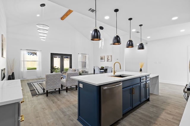 kitchen featuring stainless steel dishwasher, sink, blue cabinetry, a center island with sink, and hanging light fixtures