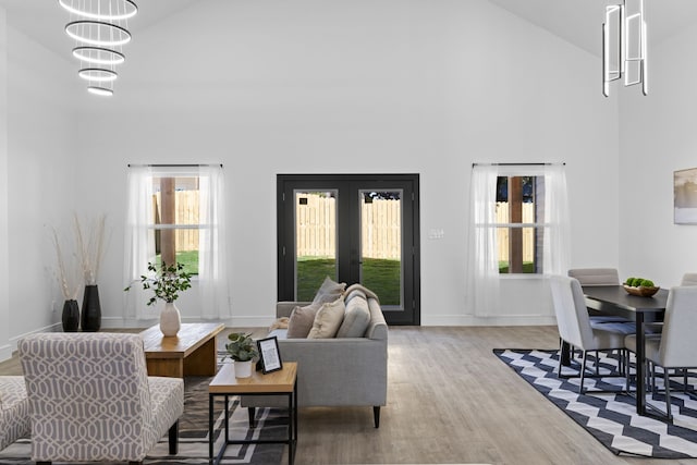 living room with light hardwood / wood-style flooring, high vaulted ceiling, and french doors